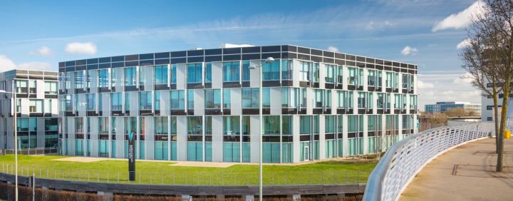 An office building with glass windows and a bridge.